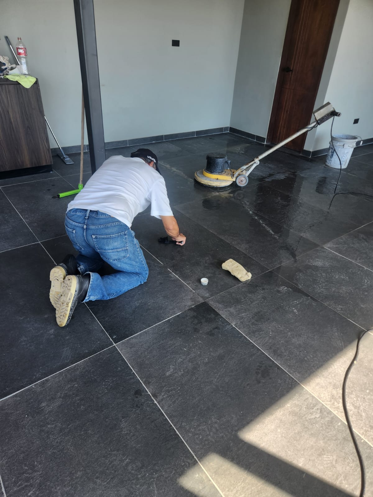 Técnico sellando junta de piso de piedra negra